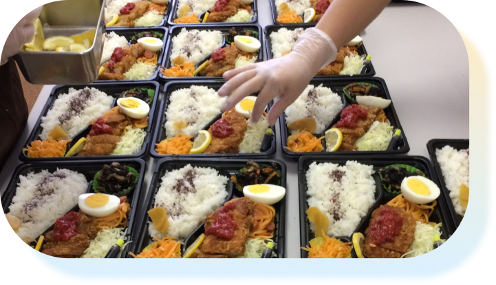 お弁当のパックを並べて盛り付けている様子
